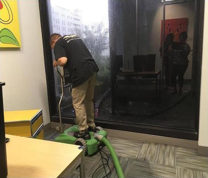 SERVPRO of Altamonte Springs/Longwood employee using a wet vacuum to dry carpets in a commercial building